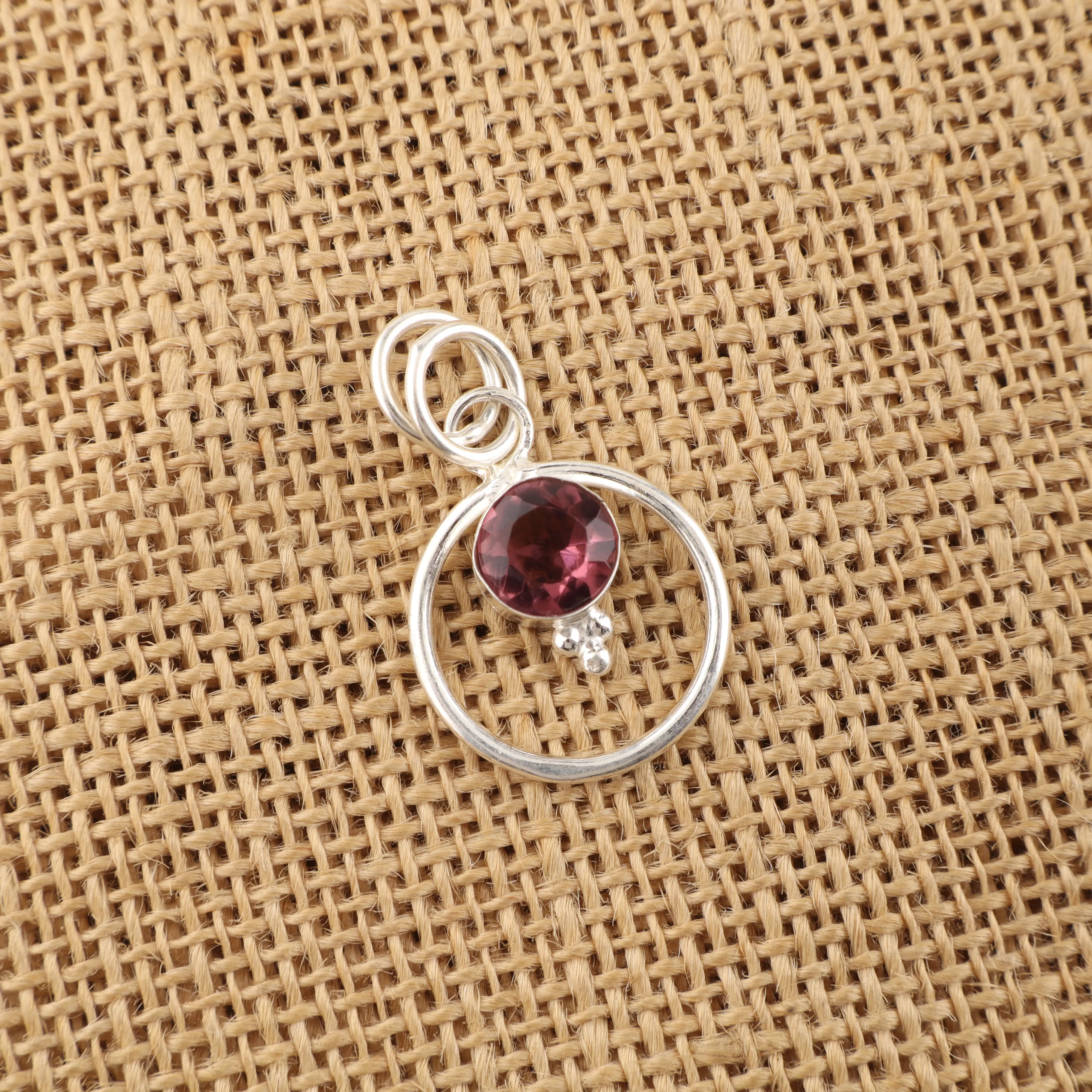 Rhodolite gemstone pendant with deep rose-red color in a handmade jewelry setting.